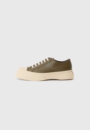 Baskets basses vert olive avec une épaisse semelle crème et des lacets blancs, présentées sur un fond blanc uni.