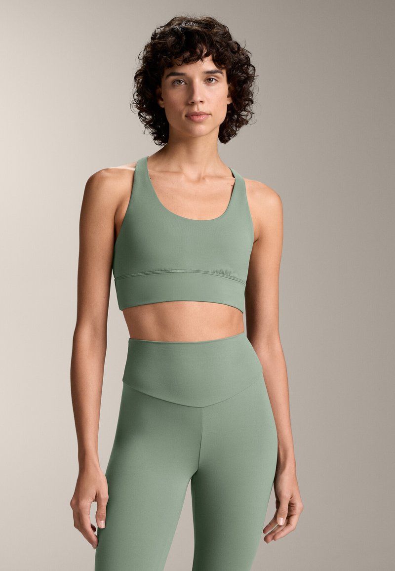 Mintgroene sportbeha en hooggesneden legging van een gladde, rekbare stof, met een ronde hals en naaddetails.