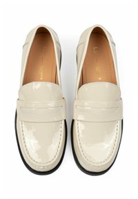 Pair of glossy cream-colored leather loafers with black soles, detailed stitching, and a strap across the top, viewed from above.