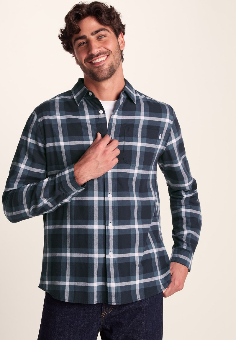 Plaid button-up shirt in navy, light blue, and gray. Cotton material, long sleeves, and a chest pocket on the left side.