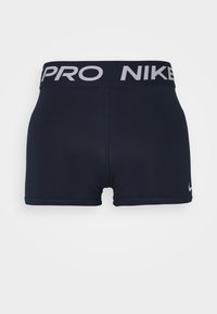 Granatowe krótkie spodenki sportowe wykonane z elastycznego materiału, z szerokim pasem w talii, na którym znajduje się logo "Nike Pro" oraz mała metka na nogawce.