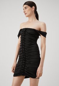Rochie neagră fără bretele, cu textură de țesătură strânsă, încrețită pe lateral și un design accentuat al cusăturii centrale. Material neted și elastic.