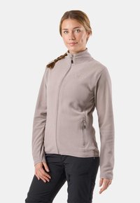 Chaqueta de forro polar beige claro con cremallera frontal, bolsillos laterales y cuello alto. Textura suave y diseño ajustado, con detalles bordados.