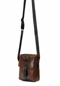 Brązowa skórzana torba na ramię z klapką, regulowanym paskiem i czarnym paskiem akcentującym z tekstem logo. Gładka tekstura, prostokątny kształt.