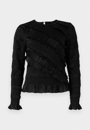 Top nero a maniche lunghe con ruffles testurizzati di larghezze variabili, con scollatura rotonda e maniche a campana. Chiusura con zip sul retro.