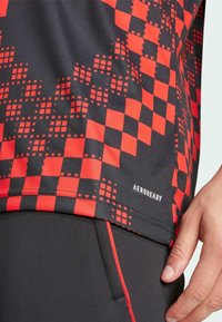 Maglietta sportiva a maniche corte con motivo a scacchi rosso e nero, realizzata in tessuto leggero e traspirante, con etichetta "AEROREADY".
