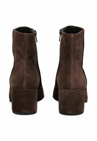 Bottes de cheville en daim marron avec un talon carré haut et des détails de fermeture éclair sur le côté. Texture lisse et forme structurée.