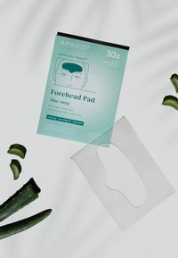 Verpakking van een voorhoofdspad gemerkt "aloe vera" met aloë bladeren en een transparant siliconen pad op een witte ondergrond.