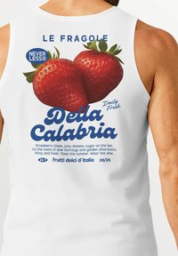 White tank top featuring a colorful graphic of strawberries, with text that includes "Della Calabria" and playful descriptions of strawberries.