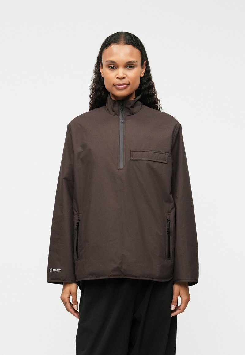 Rjava pulover jakna, visok ovratnik, pol zadrgo spredaj, žep na prsih, dva stranska žepa z zadrgo, lahkotni material, sproščen kroj, minimalističen dizajn.