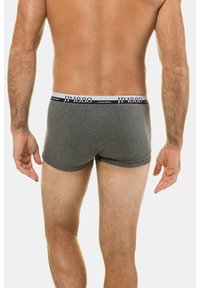 Boxer in cotone grigio con elastico bianco caratterizzato da scritte nere. I pantaloni hanno un design aderente e una superficie liscia.