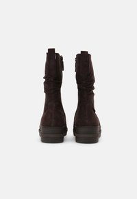 Braune Wildleder-Ankle Boots mit einem schlaffen Design, einem seitlichen Reißverschluss und einer dicken schwarzen Gummisohle. Die Rückansicht zeigt die glatte Textur und Nähdetails.
