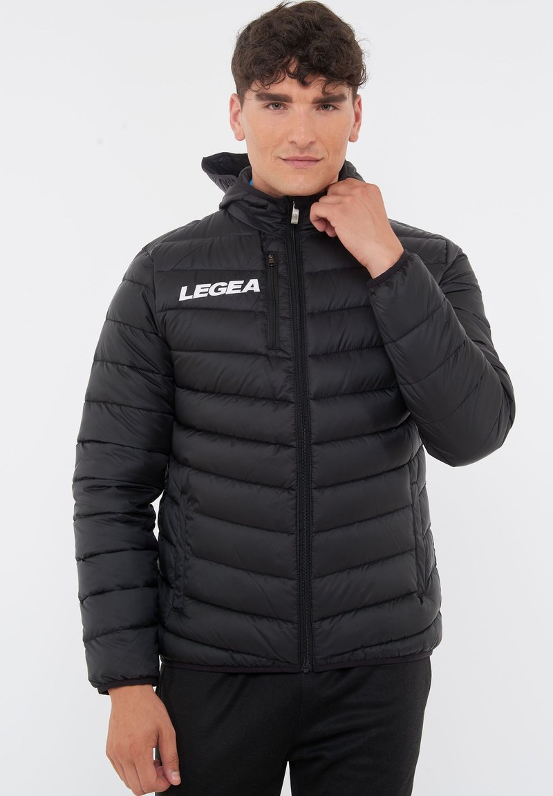 Svart puffjacka med dragkedja fram, quiltat mönster, hög krage och vit "LEGEA" logotyp på bröstet. Slät textur, slim fit.
