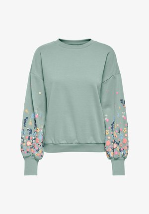 Sweatshirt vert clair avec broderie florale sur les manches, à encolure ronde, avec des poignets côtelés et une coupe décontractée. Texture de tissu douce.