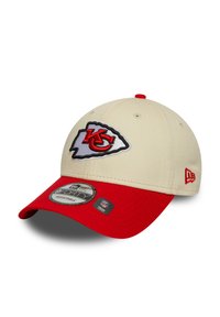 Khaki cap with red brim featuring an embroidered Kansas City Chiefs logo. Fabric is smooth with a structured shape. Adjustable strap at back.
