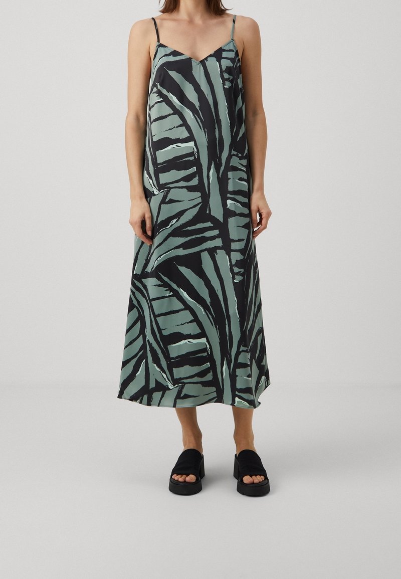 Robe longue sans manches noire et verte avec un motif de feuilles. En tissu lisse, elle présente un col en V et une silhouette fluide.