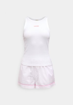 Canotta bianca senza maniche con una texture a coste e logo rosso "Calvin Klein", abbinata a pantaloni corti a strisce rosa con un bordo rosa.