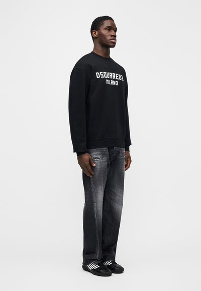 Schwarzer Sweatshirt mit "DSQUARED2 MILANO" Logo, kombiniert mit ausgewaschenen grauen Jeans und schwarzen Sneakern mit weißen Streifen. Einfach, locker sitzend.