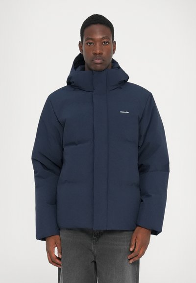 Navy blue puffer jacket with a high collar and adjustable hood, featuring a zip front, side pockets, and a quilted texture.