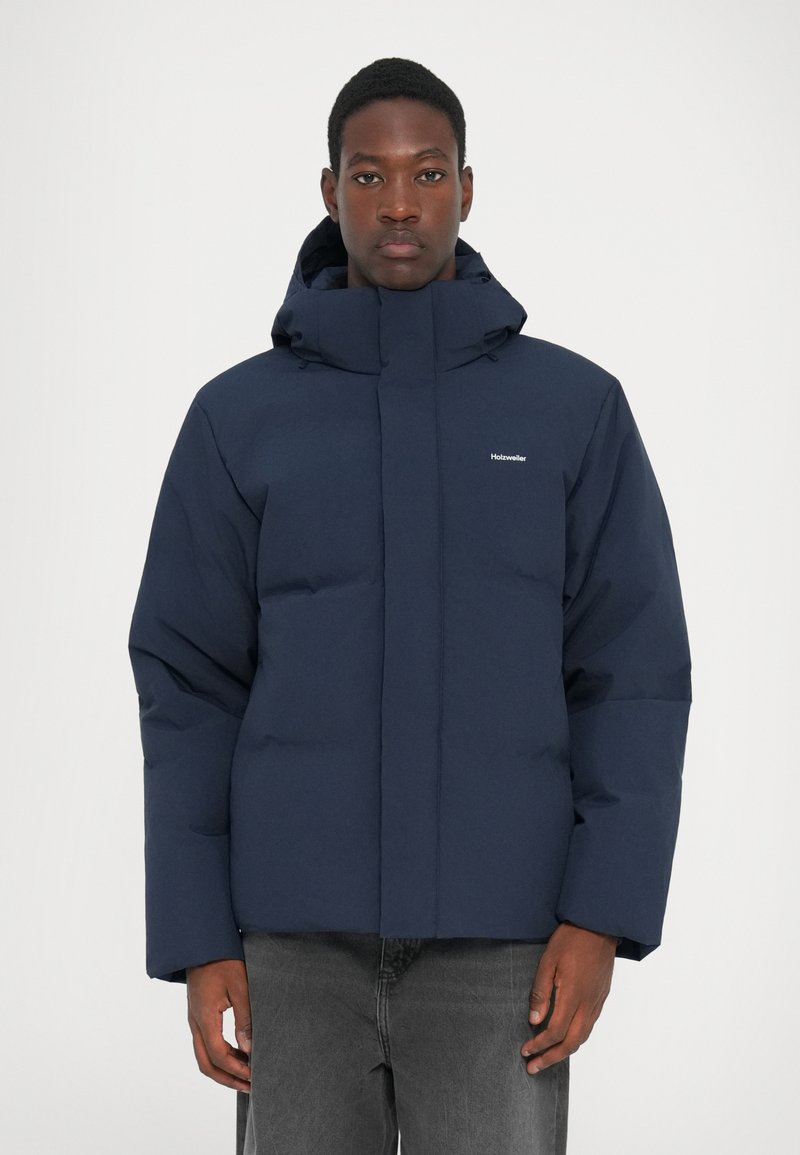 Navy blue puffer jacket with a high collar and adjustable hood, featuring a zip front, side pockets, and a quilted texture.