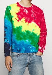Färgglad tie-dye sweatshirt med mönster i röd, gul, grön och blå. Tillverkad av mjukt tyg med rundad halsringning och ribbade muddar.