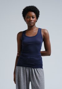 Canotta blu navy con design aderente e scollatura tonda, abbinata a pantaloni corti grigi, morbidi e larghi.
