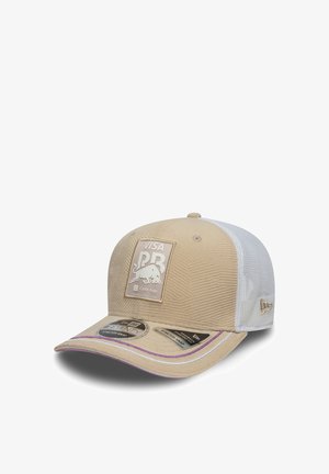 Beżowa czapka z teksturowanym wzorem, białymi siateczkowymi panelami i fioletowym akcentem na daszku. Posiada naszywkę z logo oraz regulowane zapięcie na zatrzask.