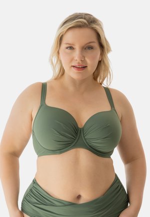 Plus-size woman with blonde hair wearing an olive green bikini top and matching high-waisted bottoms against a neutral background.