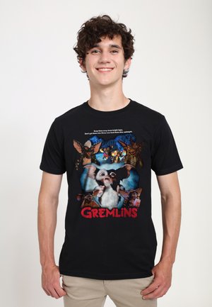 Sort T-shirt med et farverigt "Gremlins" grafik, der viser flere karakterer og tekst, rund halsudskæring, korte ærmer, lavet af bomuldsstof.