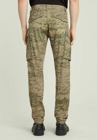 Kamouflage cargobyxor i nyanser av grönt och beige. Har sidofickor, texturerad tyg och en avslappnad passform. Bakfickor synliga.
