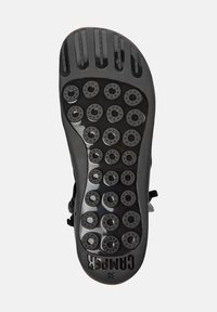 Semelle de chaussure noire en caoutchouc avec plusieurs pastilles de grip circulaires et un motif de semelle standard. Présente le nom de la marque "CAMPER" et la taille "38" en relief.