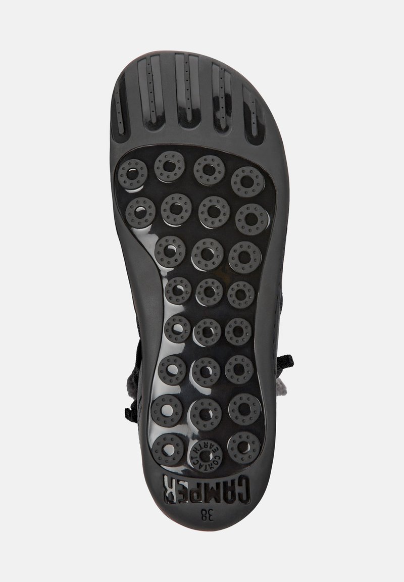 Svart gummiskosula med flera cirkulära greppdynor och standard mönster. Har varumärket "CAMPER" och storlek "38" präglat.