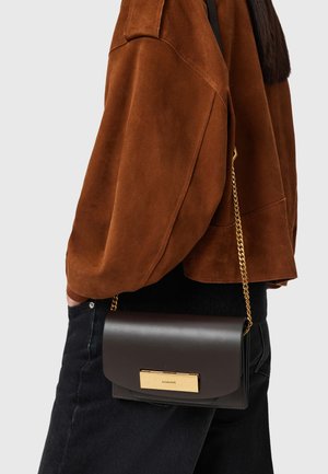 Rudis zomšinis viršus su plačiomis rankovėmis, derinamas su tamsios odos rankine, turinčia auksinį užsegimą ir grandinėlės dirželį, laikoma ties juosmeniu.