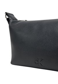 Clutch bag in pelle nera con superficie texture. Presenta un logo goffrato sottile, forma rettangolare e un'inserto in metallo.