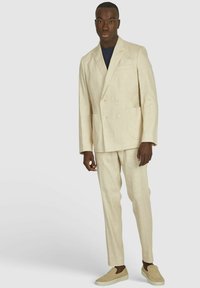 Beige linnen double-breasted pak met twee voorzakken, vergezeld van beige instap schoenen. Heeft een getailleerde pasvorm en een minimalistisch ontwerp.