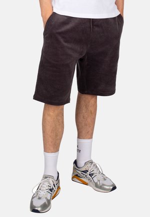 Corduroy shorts in dark gray, featuring a relaxed fit, side pockets, and a smooth texture. Paired with white socks and multicolored sneakers.