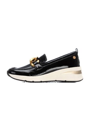 Zapato mocasín de charol negro con una decoración de hardware dorado, diseñado con una suela de cuña blanca y dorada. Textura suave, forma de punta redondeada.