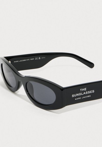 Occhiali da sole neri a forma ovale di Marc Jacobs con lenti scure, marchio "THE SUNGLASSES" sulla montatura e dettagli del modello stampati all'interno dell'astina.