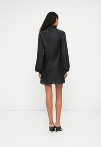 Rochie mini neagr�ă cu mâneci lungi tip balon, realizată dintr-un material transparent. Dispune de un decolteu înalt și detalii subtile ale cusăturilor pe spate.