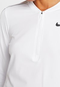 Weißes sportliches Quarter-Zip-Oberteil aus glattem Material, mit einem schwarzen Nike-Logo und dezenten Nähten entlang der Schultern.