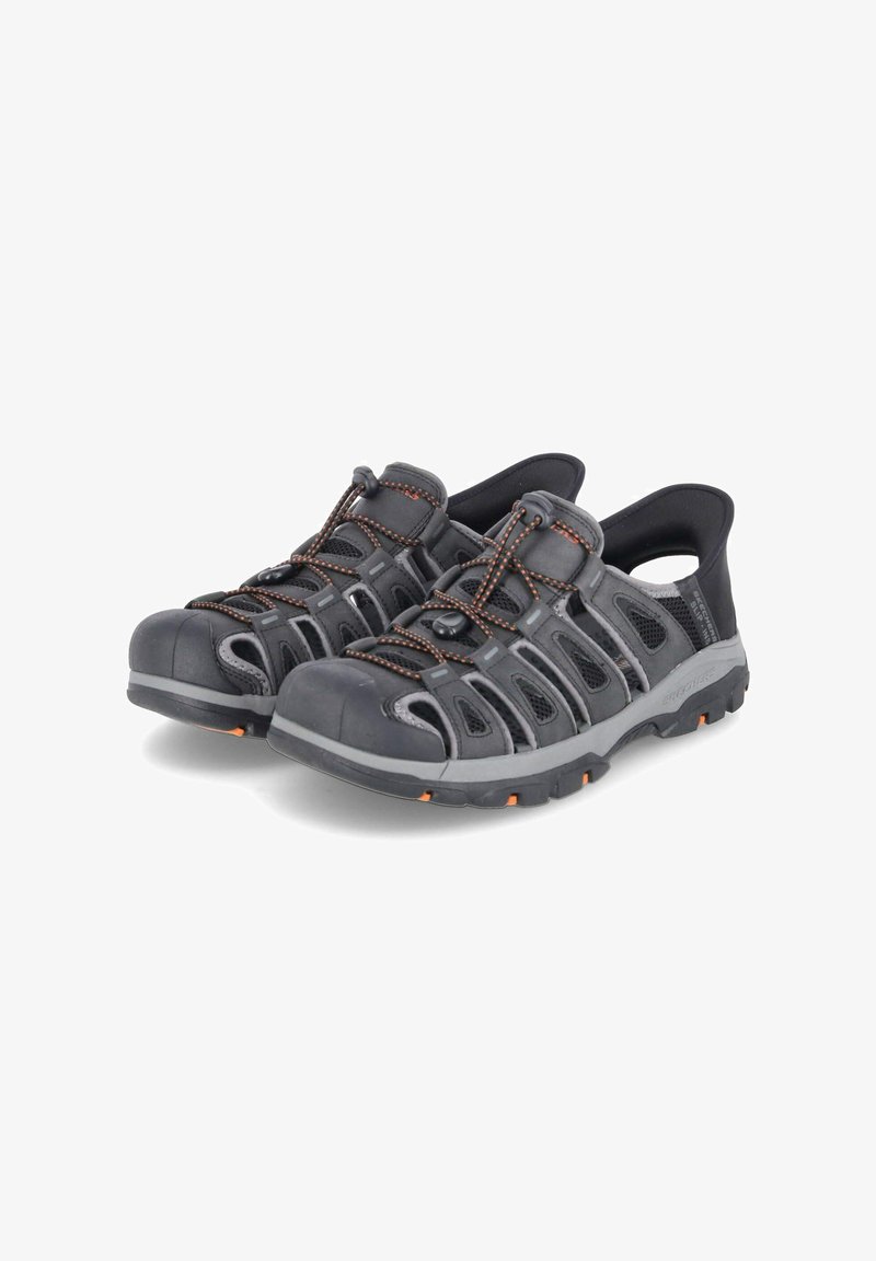 Chaussures d'eau noires avec des panneaux en mesh, des accents orange, une coque en caoutchouc pour les orteils et des lacets élastiques. Conçues pour le confort et la respirabilité.
