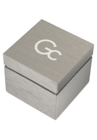 Metalen zilveren cadeau doos met een geborstelde textuur en een gladde, vlakke deksel met een witte "G" logo bovenop. Vierkante vorm met een deksel.
