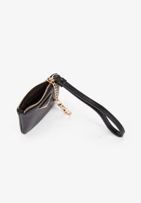 Pochette da polso in pelle nera con zip dorata e chiusura a catena, parzialmente aperta, che mostra il rivestimento interno in tessuto.