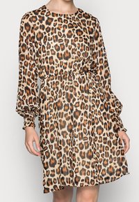 Leopardmönstrad klänning med lös passform, långa ärmar, elastiska manschetter och draperad midja. Tillverkad av ett lätt, texturerat tyg.