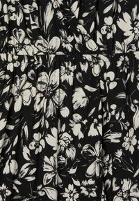 Tessuto nero con stampa floreale bianca, con fiori di forme e dimensioni diverse. Il materiale appare morbido con una texture plissettata.