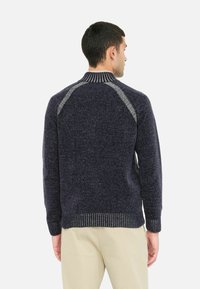 Pulover tricotat navy cu un finisaj texturat, având un guler și manșete cu model în ribi, și accente contrastante de gri deschis pe cusăturile umerilor.