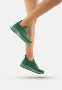 Sneakers verde slip-on con toma superiore in maglia testurizzata e suola in gomma semi-trasparente, privi di lacci e con dettagli di design minimi.