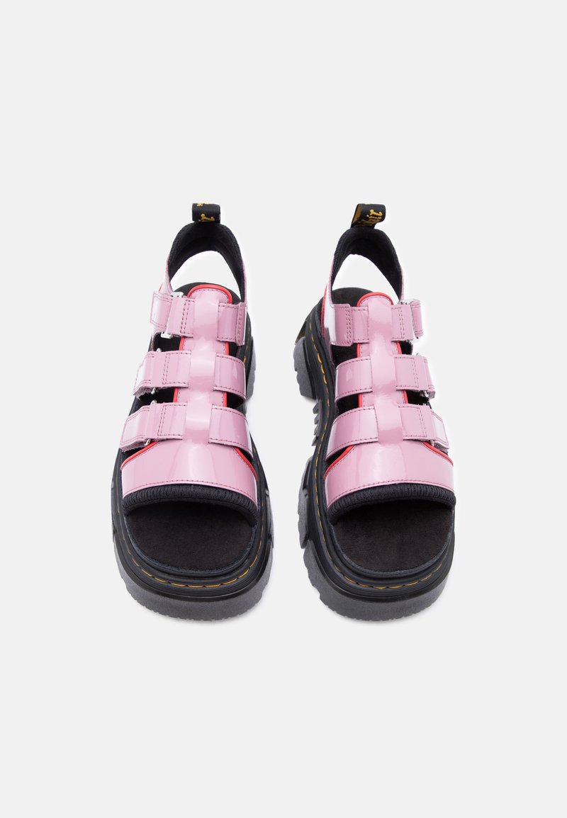 Sandali robusti con suola nera, tripli cinturini rosa lucido, dita aperte e linguette sul tallone, mostrati frontalmente su sfondo chiaro.