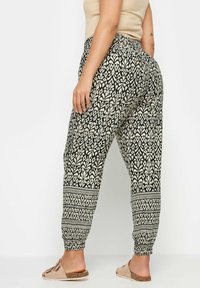 Svart och krämfärgade mönstrade joggerbyxor med elastiska mudd och midja, med en blommig design och kontrasterande kant vid vristerna.