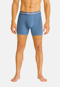 Blauwe boxershorts van een gladde stof, met een contrasterende tailleband waarop subtiel de "CR7" branding staat.
